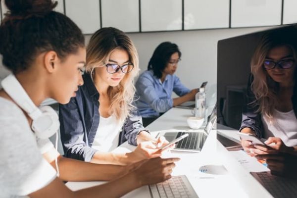 pretty-freelance-copywriter-texting-message-phone-while-her-colleagues-typing-keyboards-indoor-portrait-young-programmers-different-ethnicities-working-office_197531-3697